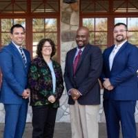 Four award recipients pose and rotate together outside of Alumni House